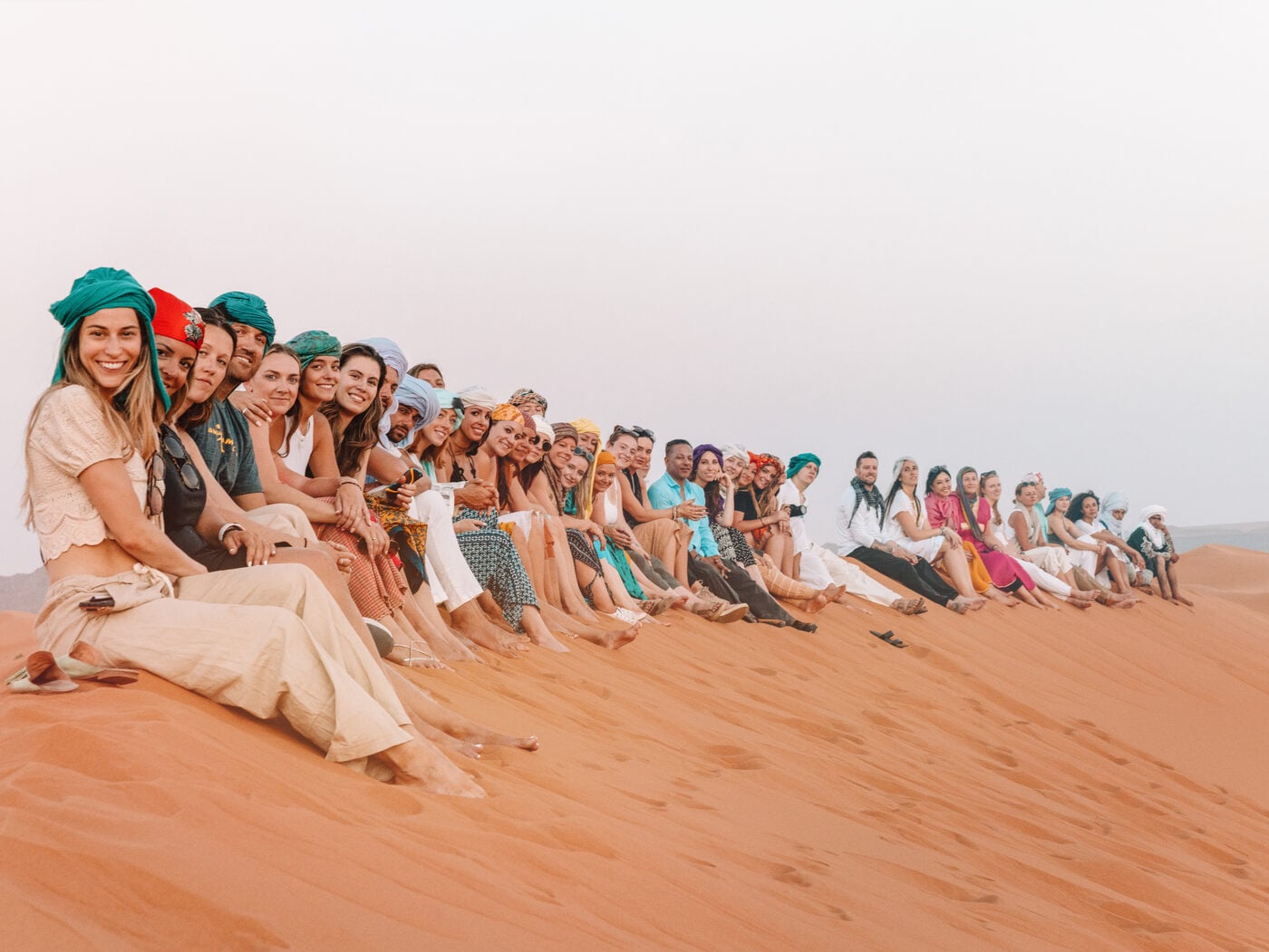 An SYB crew sitting in a line on top of a sand dune in the Sahara