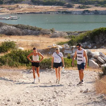 Three friends walking up a trail with a bay behind them on the SYB Turkey trip