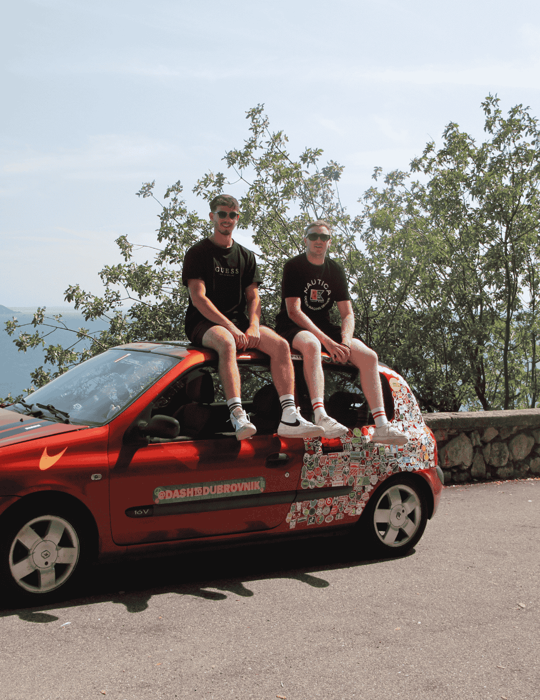 Two university students sat atop car with ocean behind them during their European roadtrip from Dover to Dubrovnik.