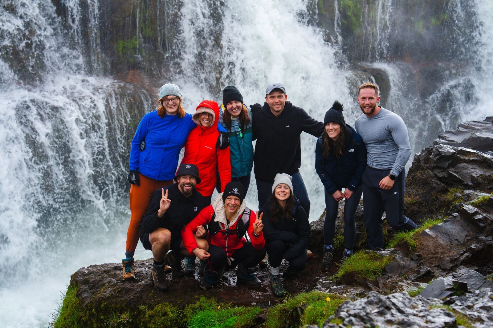 The SurfYogaBeer crew in front of a waterfall in North Iceland