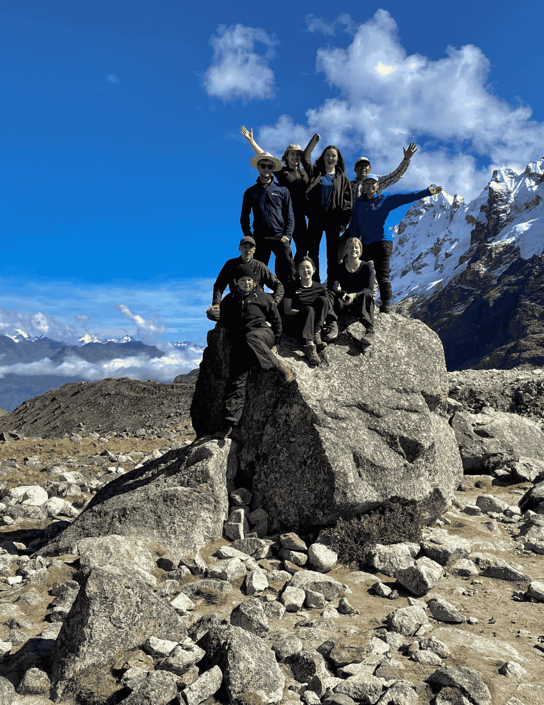 Group of students standing at the summit of the Salkantay pass 4,650m elevation with clear skies.
