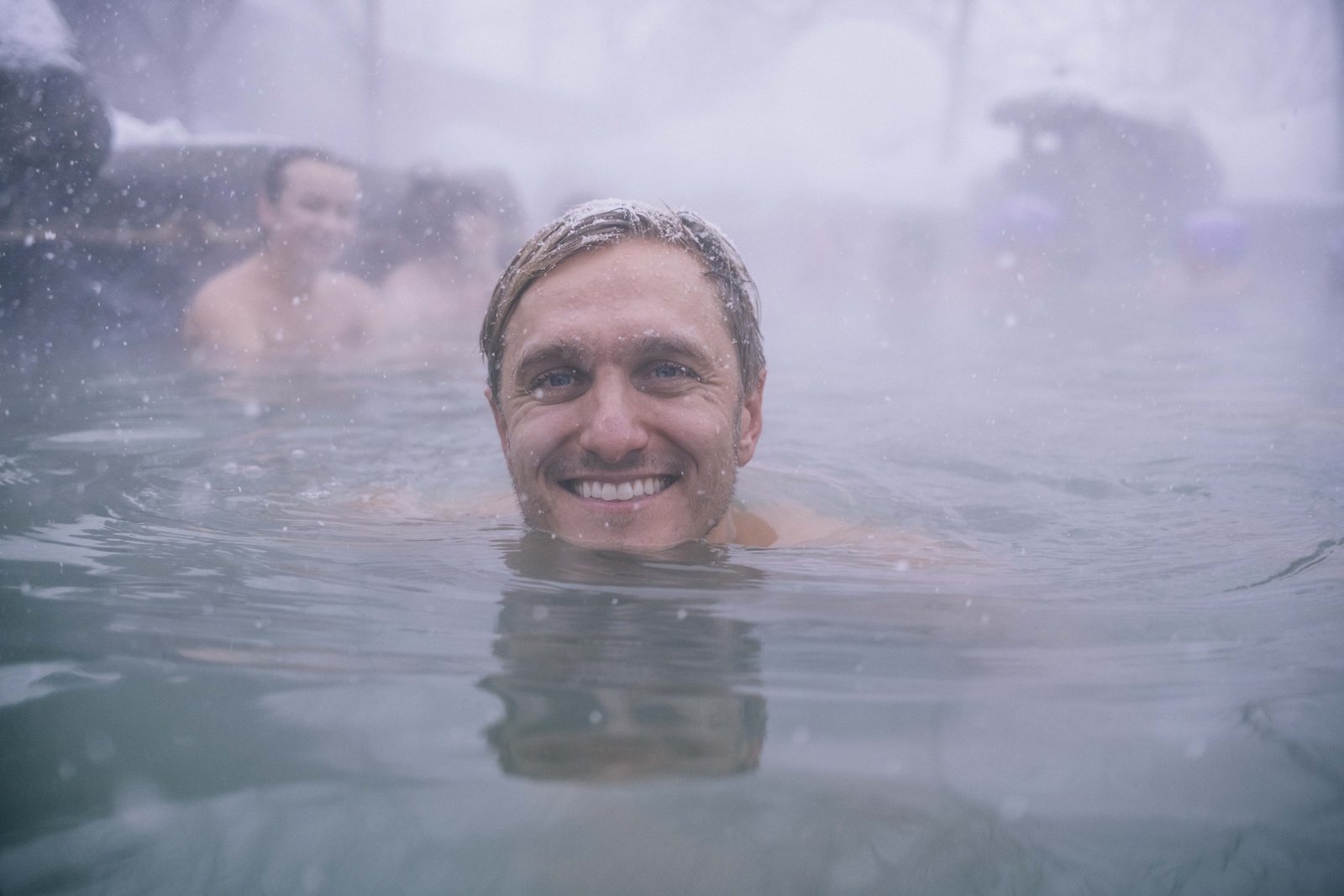 Mantas smiling in a steaming outdoor hot spring in the snow in Japan