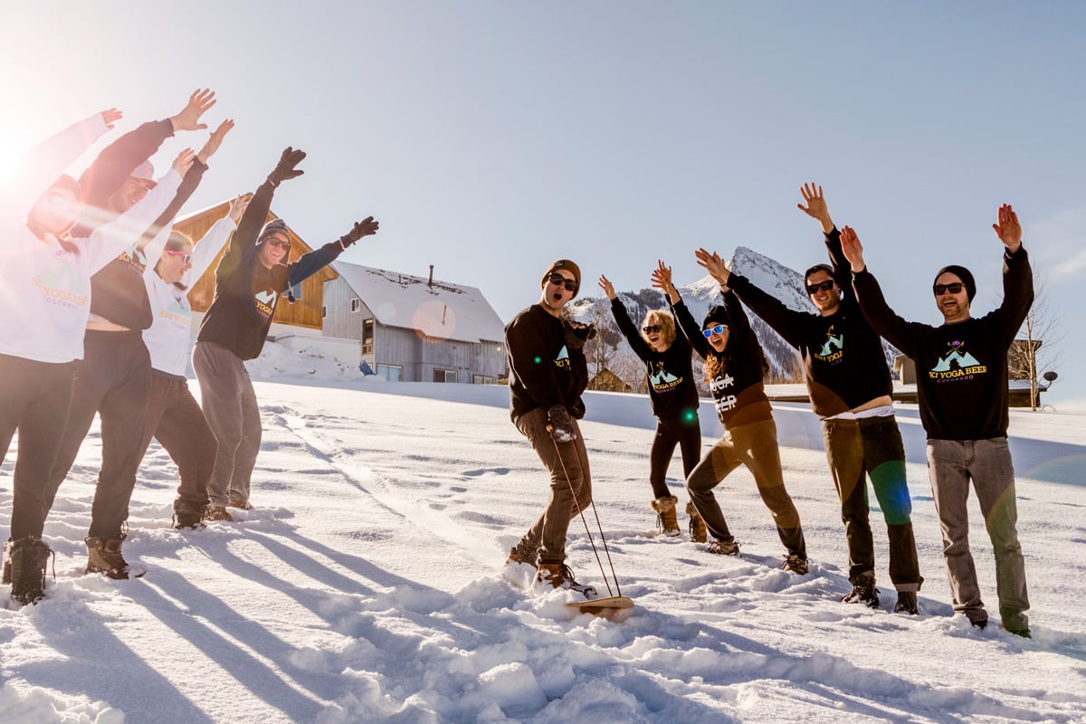 An SYB ski crew cheering in a line on the snow