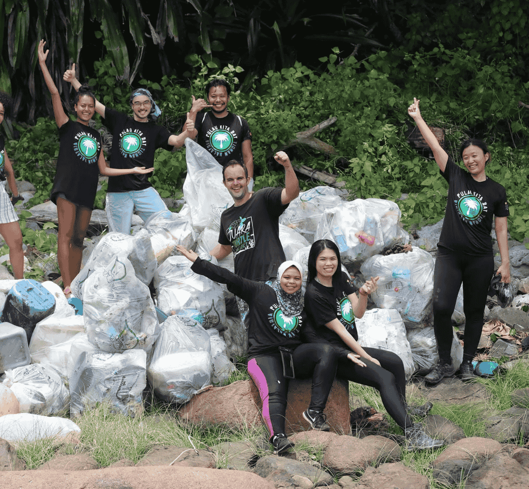 Group of Travellers against plastic volunteers packing rubbish into bin bags by river.