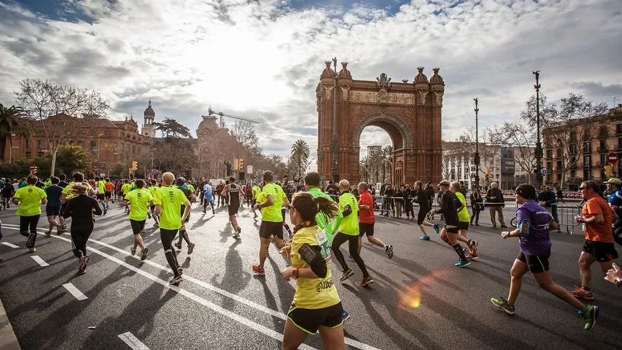 Barcelona Marathon runners approaching the Arc de Triomf on race day.