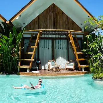 Floating in the turquoise pool in front of a peaked roof villa on the SYB Bali trip