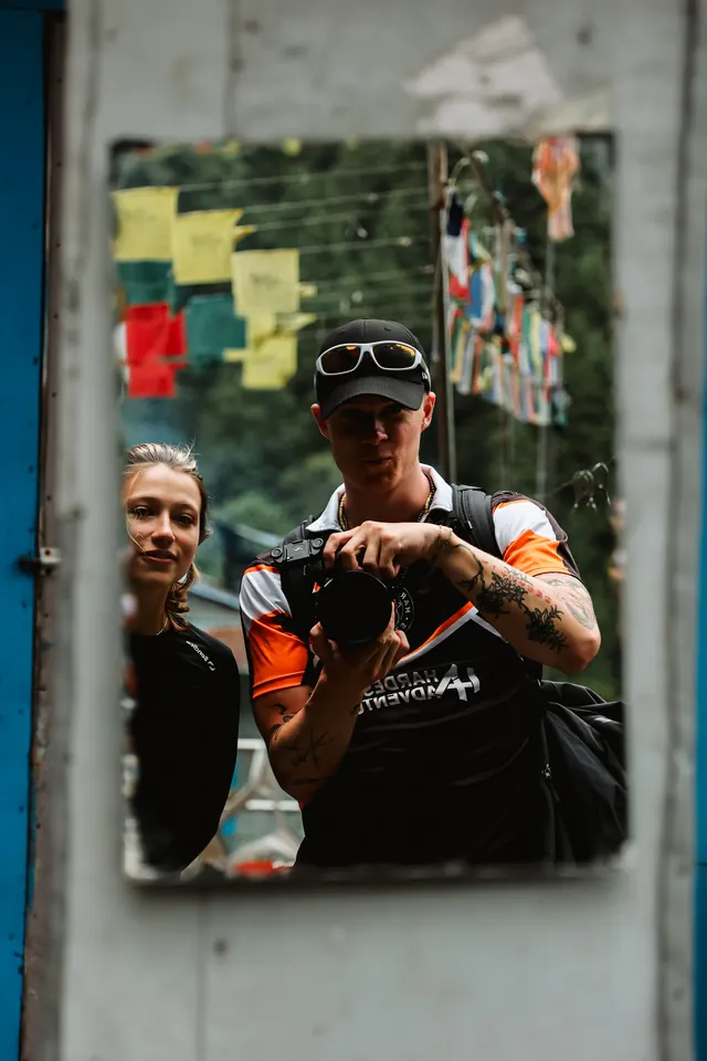 Trekkers reflected in a teahouse mirror hung with prayer flags at Phakding