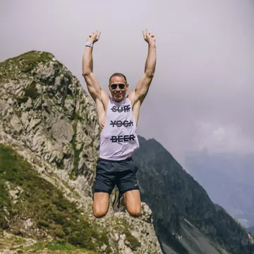 Hiker jumping with arms up on a rocky ridge on the SYB Dolomites trip