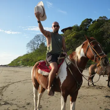 Horseback riding on the beach in Nicaragua, hat in the air