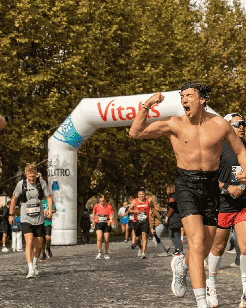 Runners cheering as they cross a finish arch