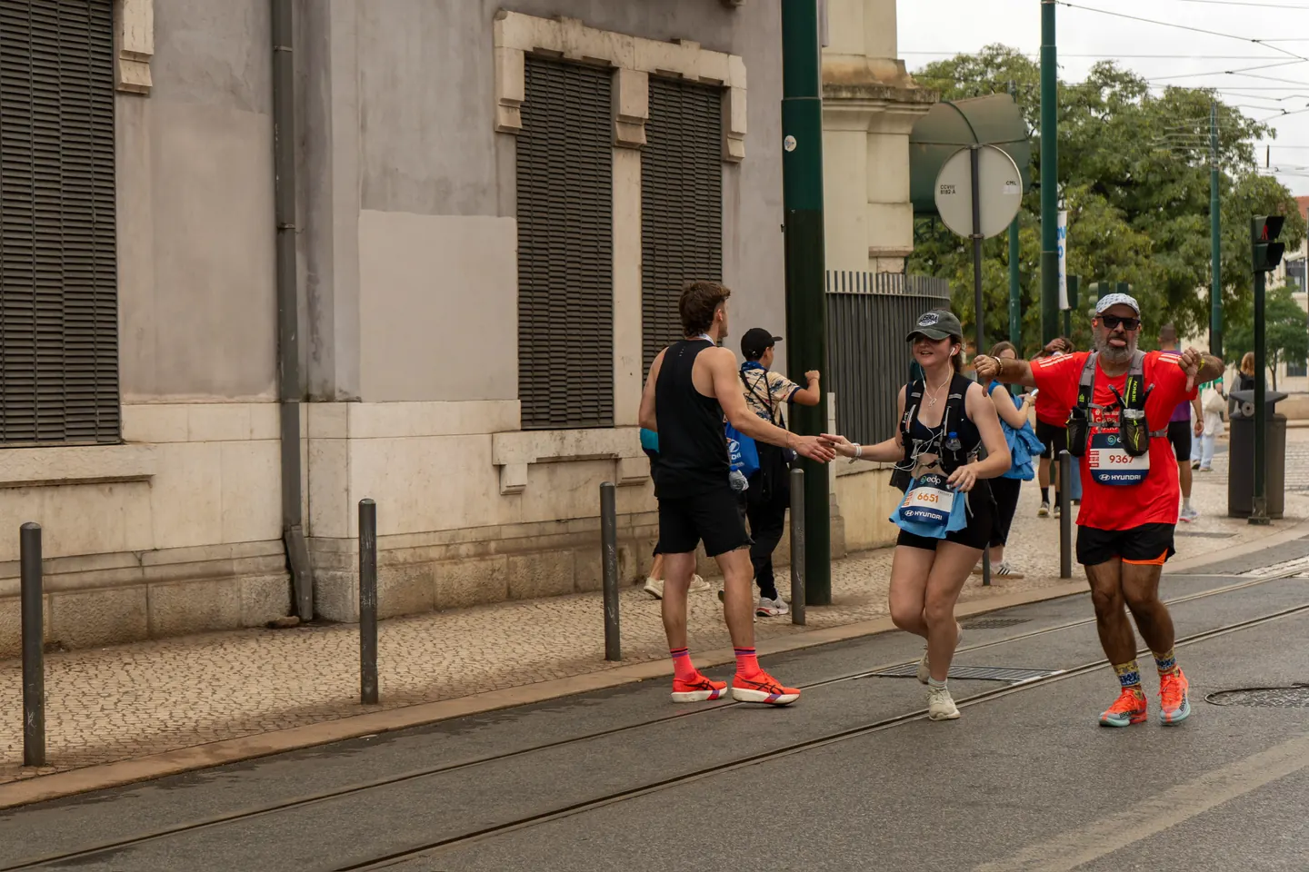 Runner striding past a classic yellow Lisbon tram on a cobbled street during the Lisbon Marathon with Hardest Adventures.