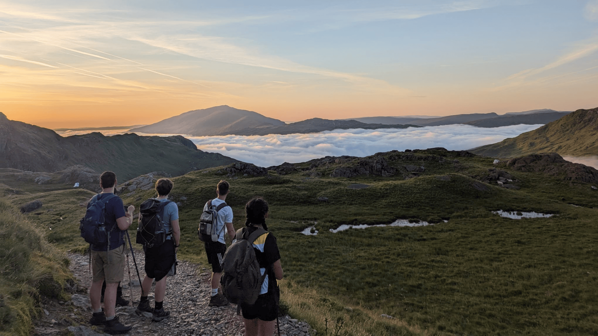 Group of hikers summiting scafell pike with hardest adventures on their corporate outdoor team-building challenge.