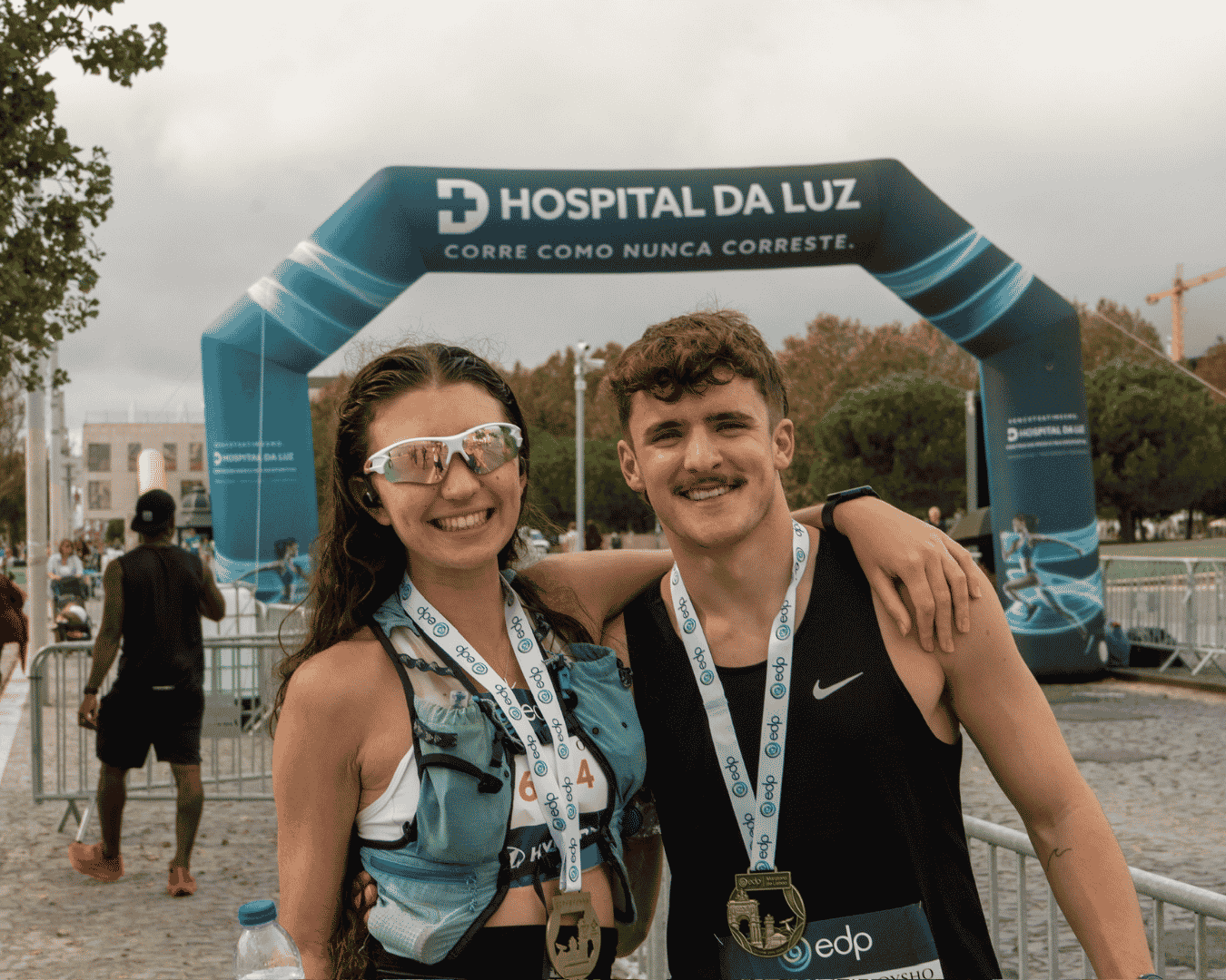 Two runners smiling and hugging with their Athens marathon medal around their neck.