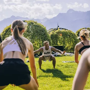 Outdoor squat workout on the lawn with mountains behind on the SYB Dolomites trip