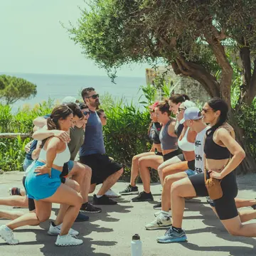 Group lunges under an olive tree by the sea on the SYB Amalfi Coast trip