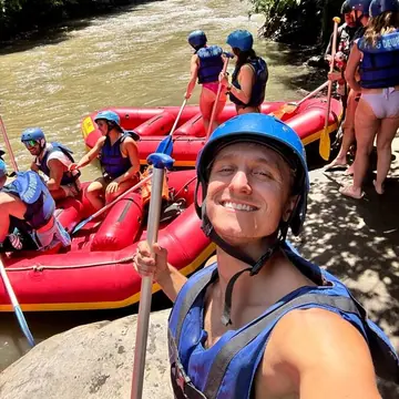Selfie in a helmet beside the red rafts on a jungle river on the SYB Bali trip