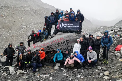 The whole Hardest Adventures group with their banner on the Everest Base Camp rock at 5,364 m