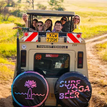 Crew looking out of the open roof of a safari jeep with Surf Yoga Beer wheel covers in Kenya