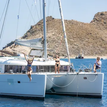 Friends on the bow of a catamaran anchored off a rocky island on the SYB Greece trip