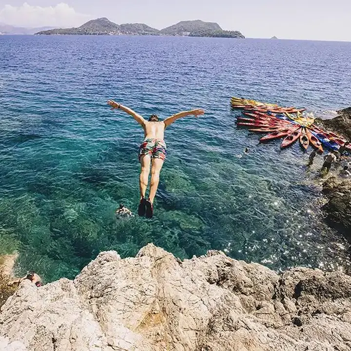 Jumping off the rocks into clear turquoise water on the SYB Croatia trip