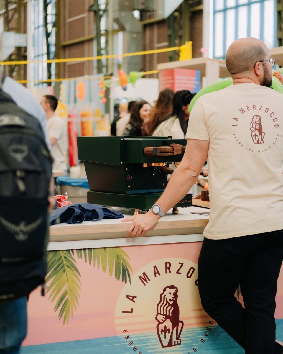 A barista leans on the La Marzocco bar in the busy NDSM hall