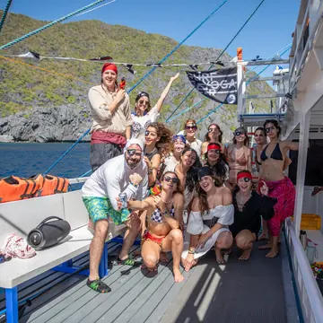 The crew posing on the boat deck with a Surf Yoga Beer flag on the SYB Philippines trip