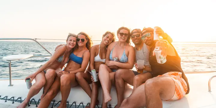 Friends sitting on the bow of the catamaran at sunset