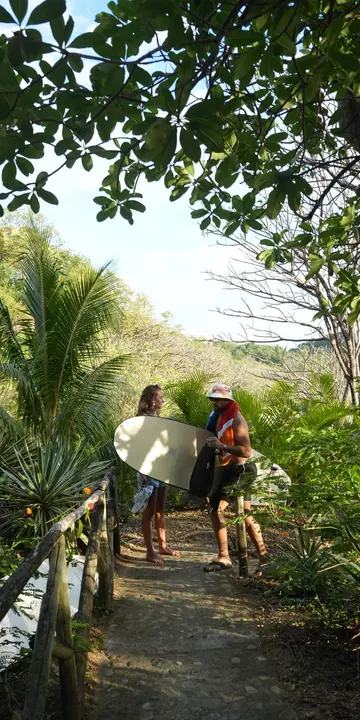Carrying a board down the jungle path to the beach on the SYB Nicaragua Surf Camp trip