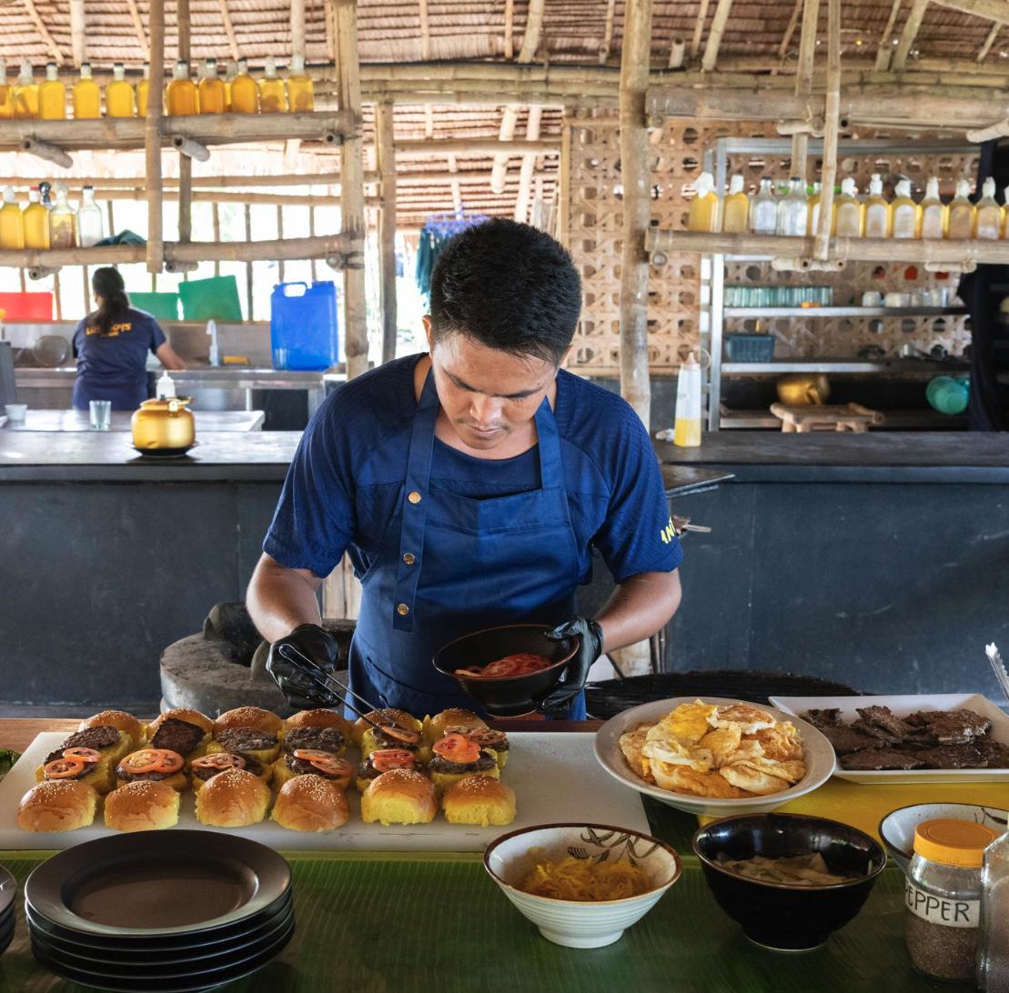 The private chef plating a spread of fresh food in the open air camp kitchen in Palawan