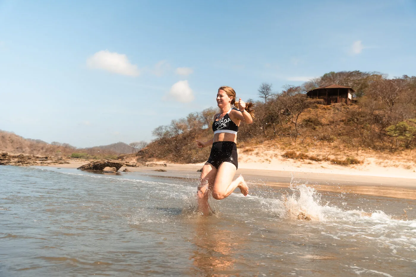 A traveler running through the shallows at Playa Maderas, Nicaragua