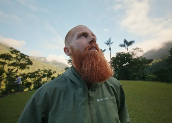 Russ Cook, aka Hardest Geezer, looking up in awe, surrounded by jungle and clear skies, after reaching the Lost City of Colombia with Hardest Adventures.