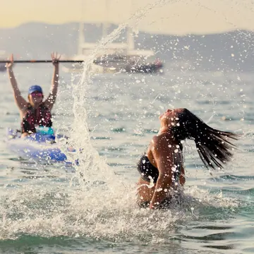 Hair flip splash in the sea next to a kayaker holding a paddle overhead on the SYB Croatia trip