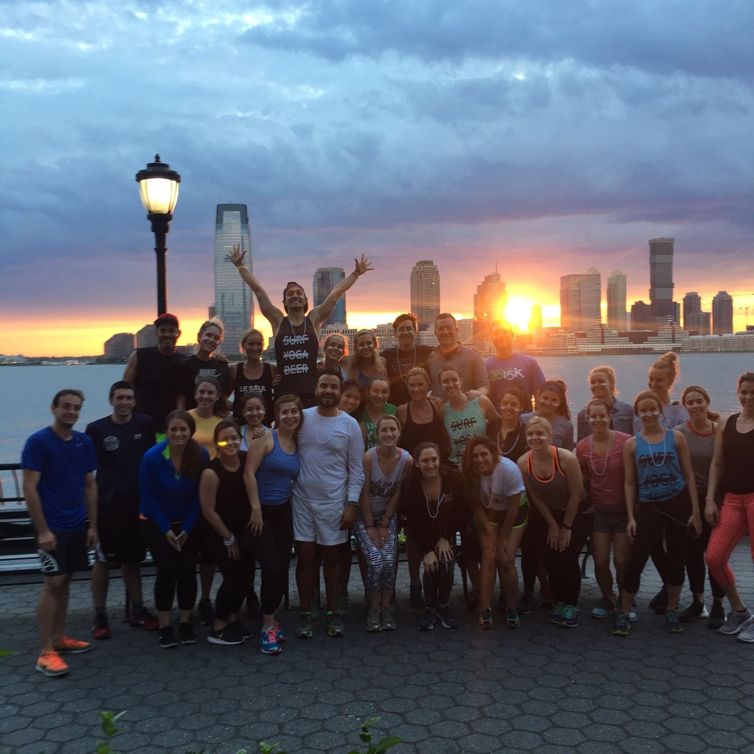 The SurfYogaBeer Run Club, about thirty five people together at sunset on the Hudson River in New York