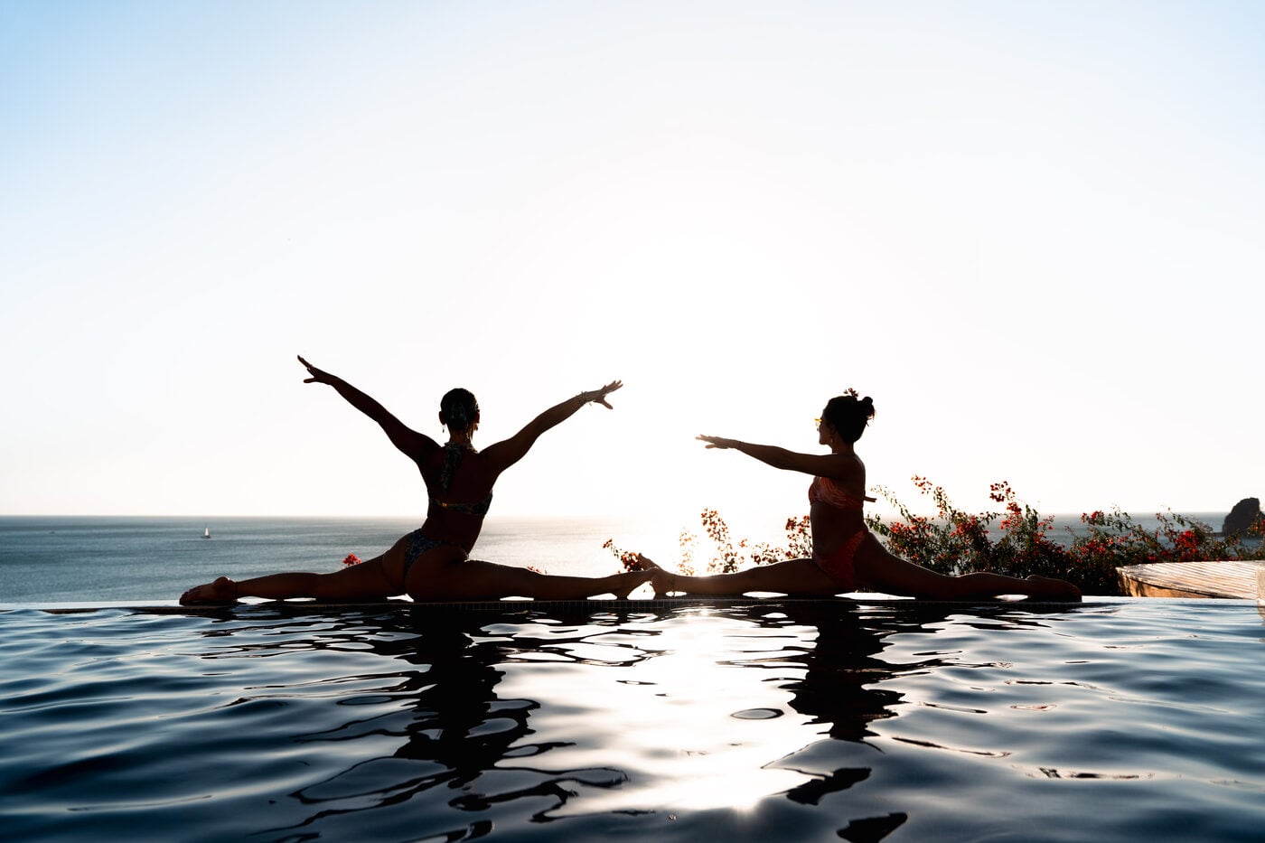 Two people practising yoga in silhouette at sunset above the Pacific in Nicaragua