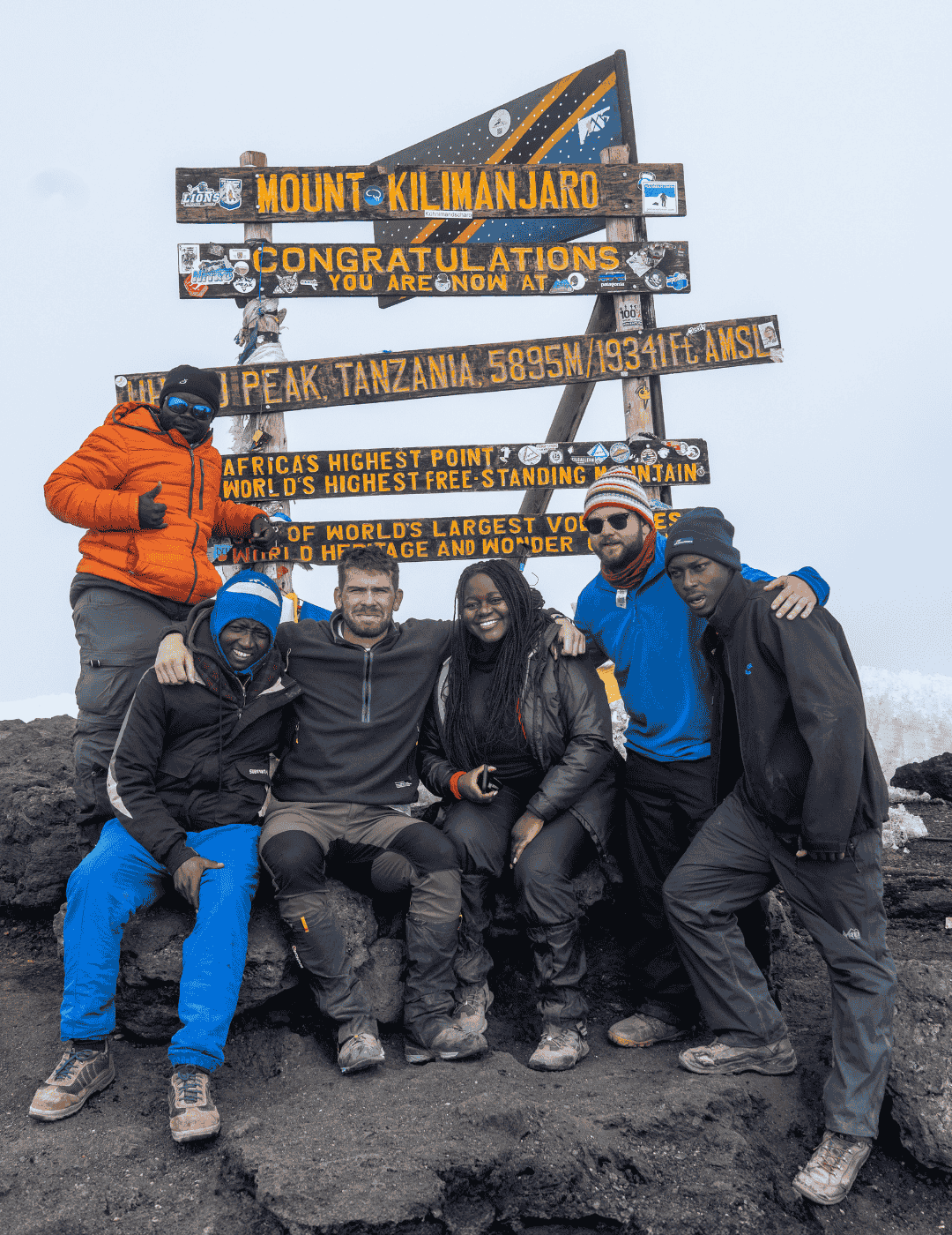 Group of hikers celebrating summit atop Kilimanjaro after completing their trek with Hardest Adventures.