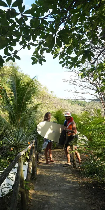 Walking the jungle path down to the surf with boards