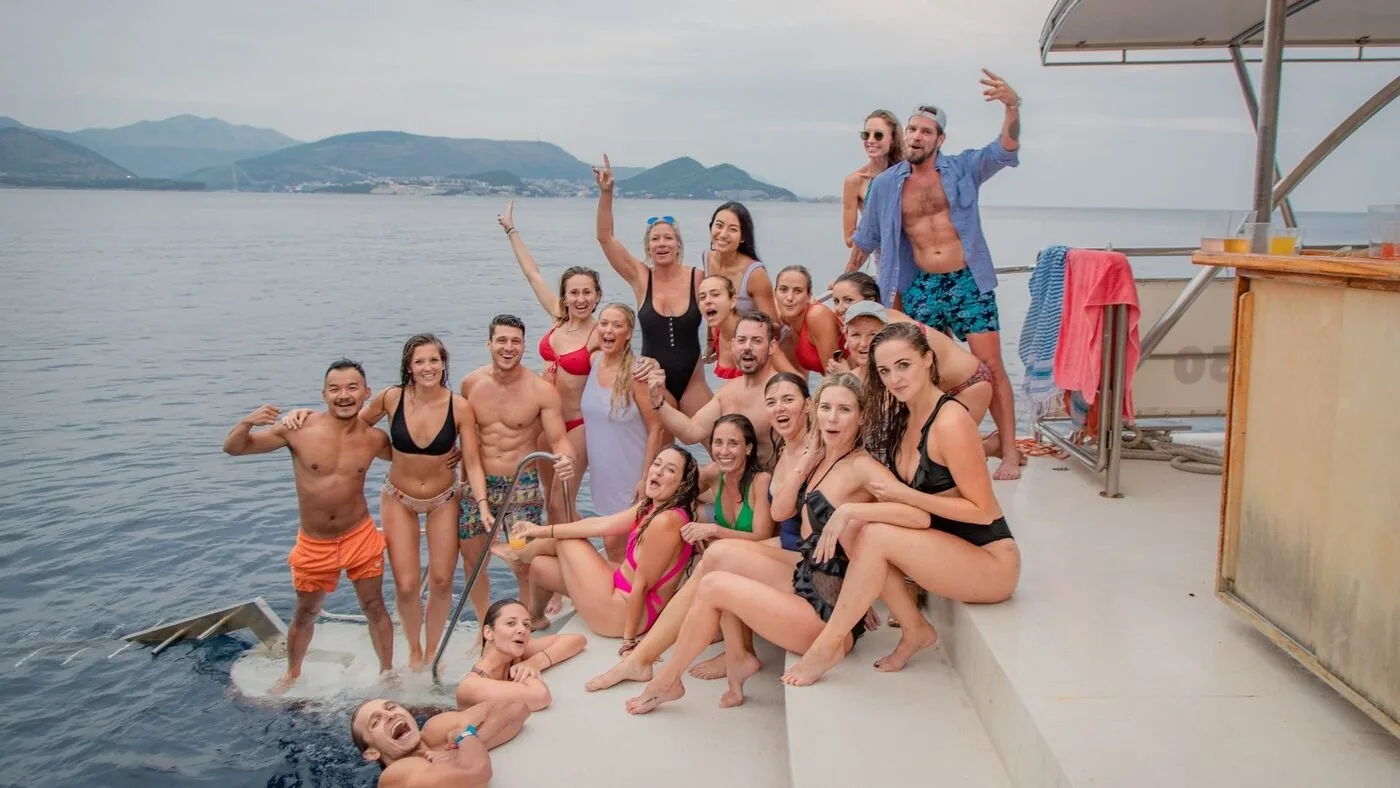 An SYB crew in swimwear cheering by the sea with the islands behind, on the Croatia trip