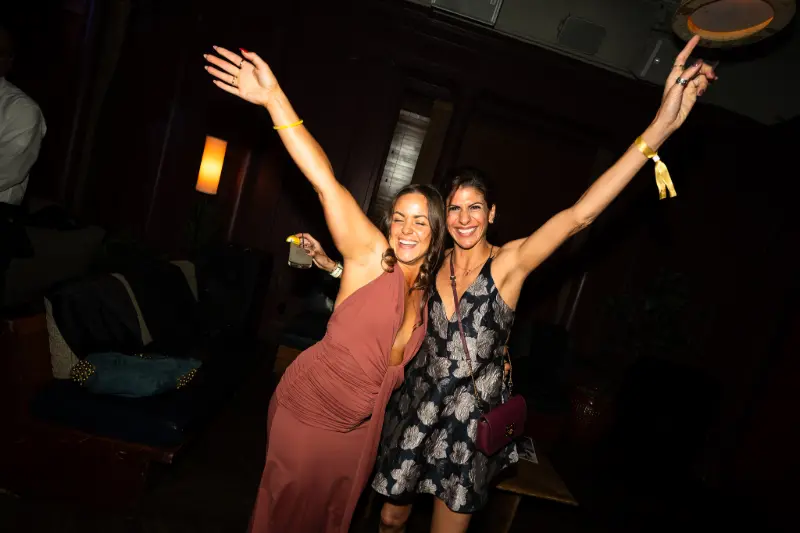 Two friends with their arms up on the dance floor