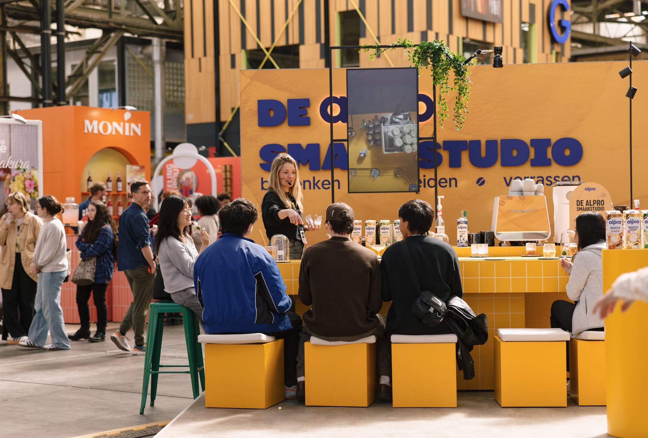 Visitors seated at the Alpro stand bar at the Amsterdam Coffee Festival