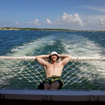 Relaxing on the boat net with the wake trailing behind on the SYB Bali trip