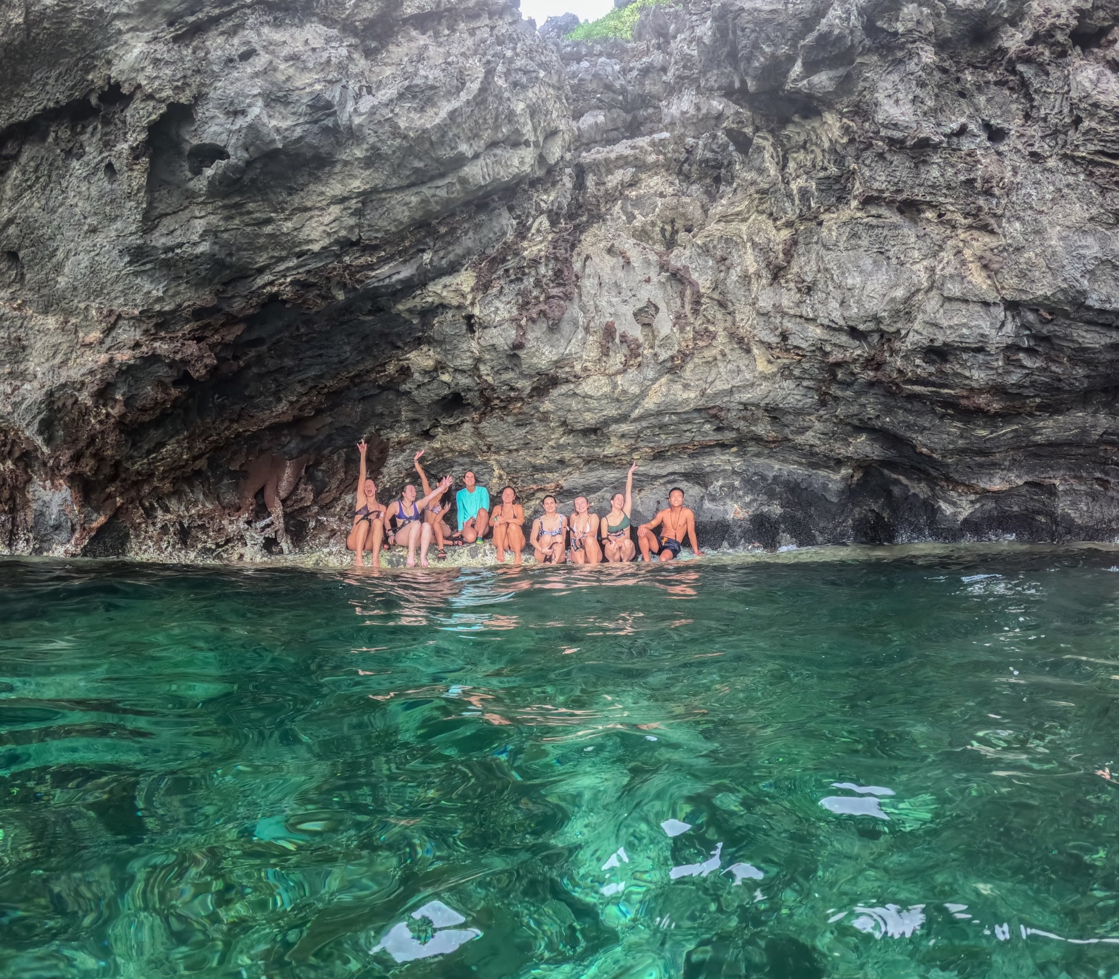 SurfYogaBeer crew swimming in clear green water under the cliffs in Palawan