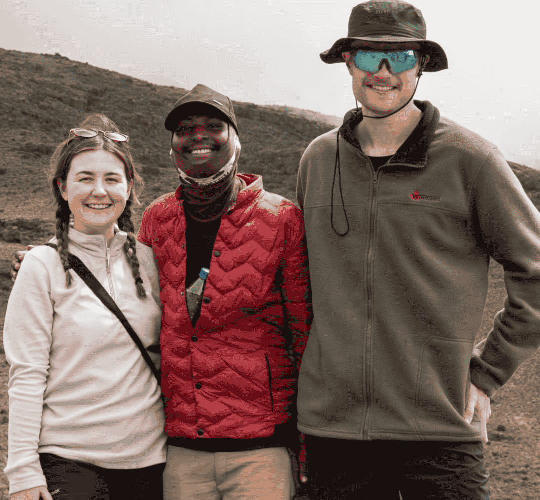 Two young Hikers standing with KPAP accredited guide climbing mt kilimanjaro with Hardest Adventures.