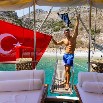 Holding a Turkish flag on the back of the gulet in a turquoise bay on the SYB Turkey trip