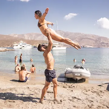 Partner lift on the sand with boats anchored in the bay on the SYB Greece trip