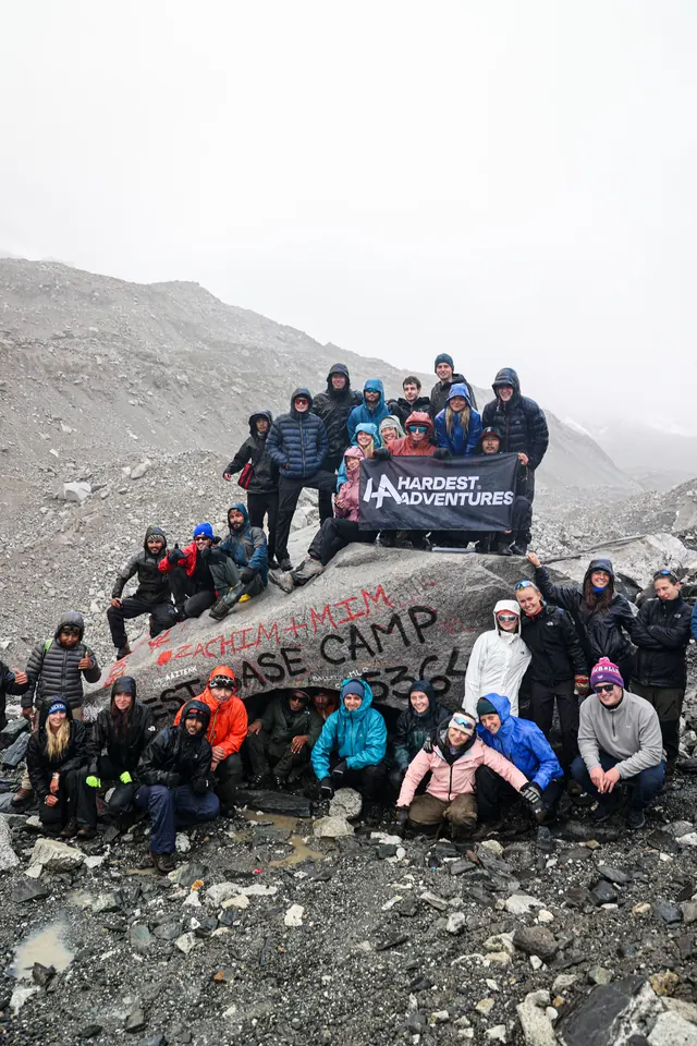 Hardest Adventures trekkers gathered round the Everest Base Camp rock with their banner