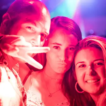 Three friends taking a selfie under club lights on the SYB Greece trip