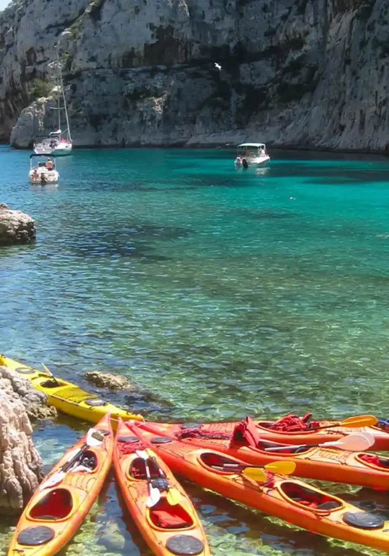 Kayaks lined up in a turquoise calanque near Cassis on the SurfYogaBeer South of France trip