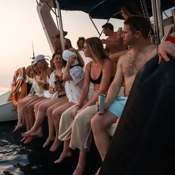 Friends sitting along the side of the catamaran at sunset on the SYB Nicaragua Surf Camp trip