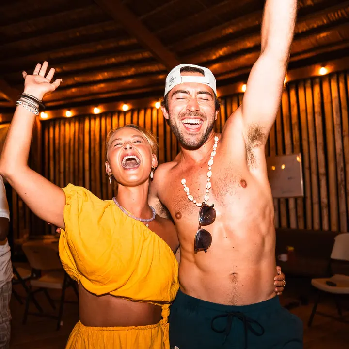 Two friends cheering with arms up at the villa party on the SYB Nicaragua trip