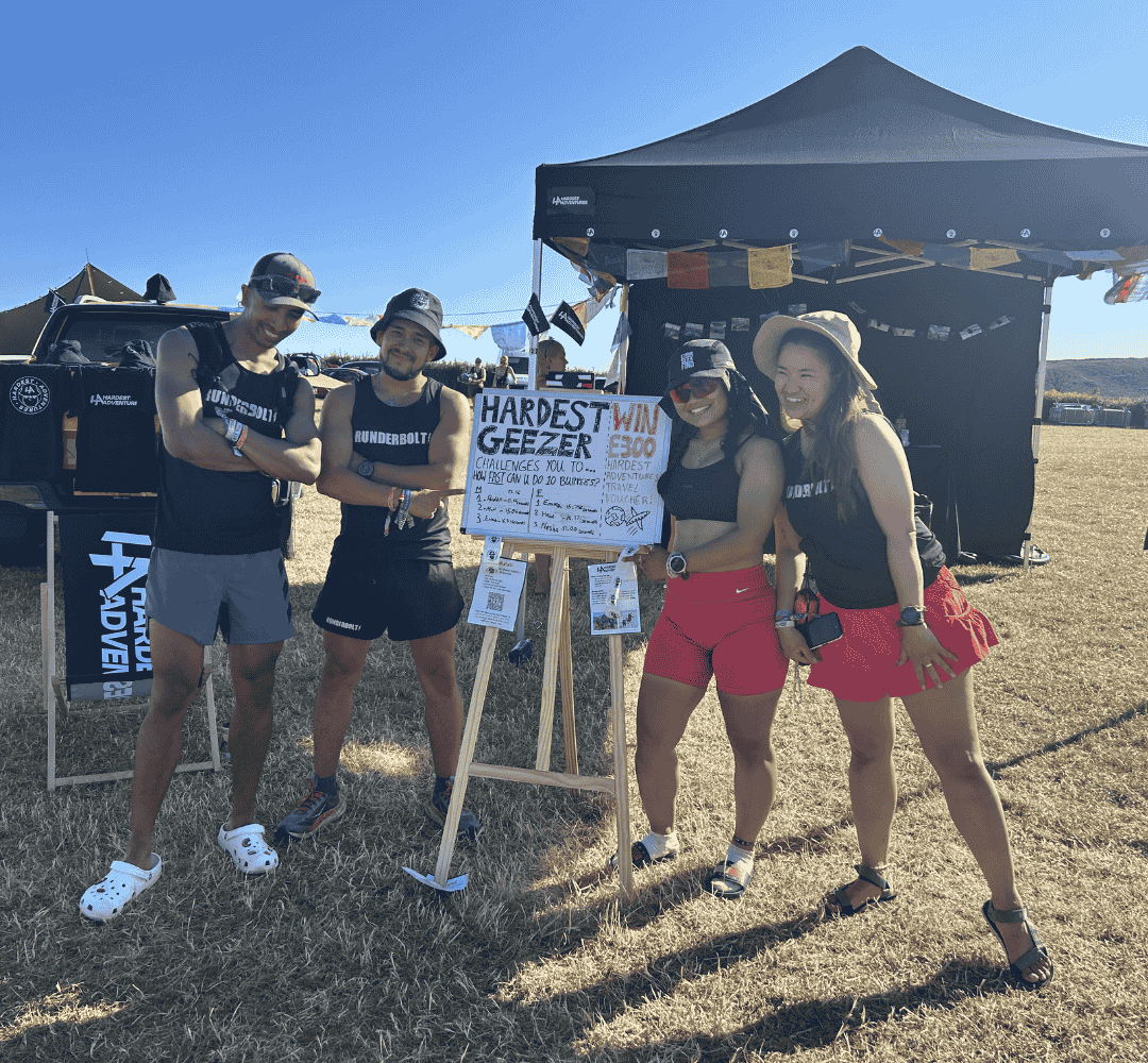 Group of young adventurers standing around whiteboard with fitness challenge from Hardest Geezer written on it.
